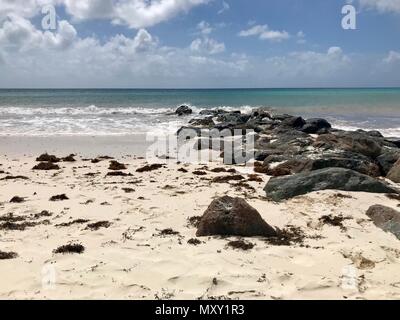 Pittoresque idyllique plage de la Barbade (île des Caraïbes des Antilles) avec de grandes pierres noires, du sable blanc et une mer turquoise avec un ciel bleu clair Banque D'Images