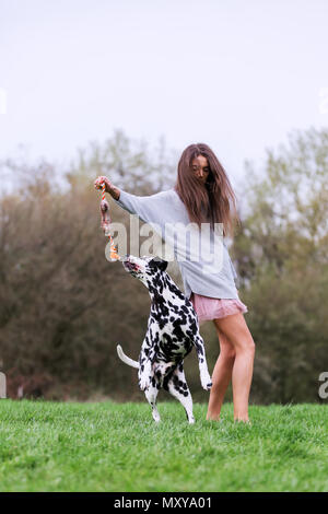 Jolie jeune femme joue avec un chien dalmatien sur le pré Banque D'Images
