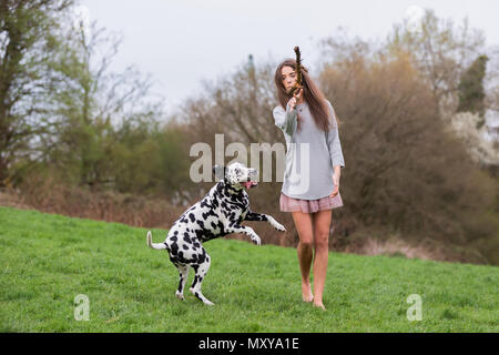 Jolie jeune femme joue avec un chien dalmatien sur le pré Banque D'Images