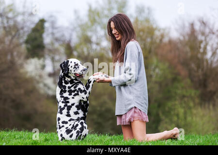 Jolie jeune femme joue avec un chien dalmatien sur le pré Banque D'Images