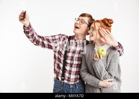 Smiling couple d'école Nerds prendre avec un téléphone mobile selfies isolated over white background Banque D'Images