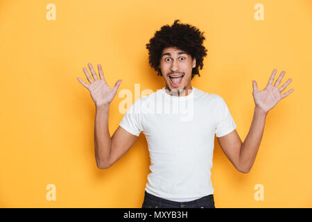 Portrait d'un jeune africain excité guy hurlant de mains posées sur fond jaune isolé Banque D'Images