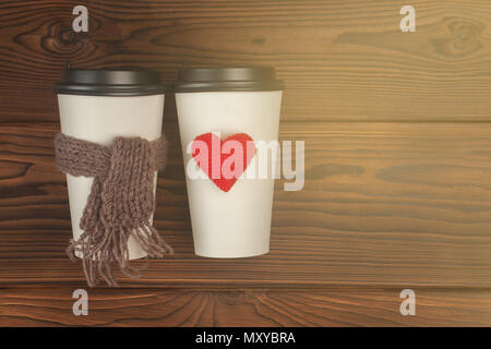 Deux tasses de café pour aller dans du papier blanc tasses dans la lumière du soleil. Café du matin pour un couple dans l'amour. Coeur de tricot et écharpe. Place pour le texte. Photo couleur Banque D'Images