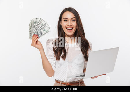 Portrait d'une femme d'satisfaits tout en maintenant des billets d'argent montrant un ordinateur portable isolé sur fond blanc Banque D'Images