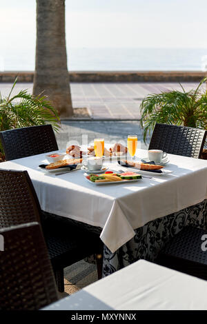 Restaurant en plein air. Réglage de la table avec petit déjeuner classique. Le jus d'Orange, fruits et pâtisseries Banque D'Images