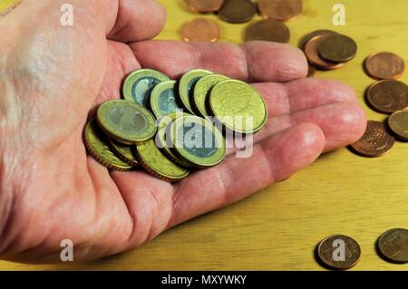 La main des hommes avec les pièces en euros et centimes sur fond de bois. Banque D'Images