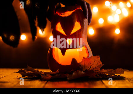 Photo de halloween citrouille coupées en forme de visage avec la main de la sorcière Banque D'Images