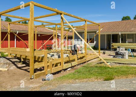 Menuisiers travailler à l'extérieur sur l'érection d'une grande terrasse avec pergola et un foyer rond Banque D'Images