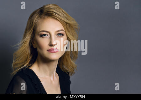 Close-up studio portrait d'une belle femme blonde d'âge moyen. Fond gris Banque D'Images