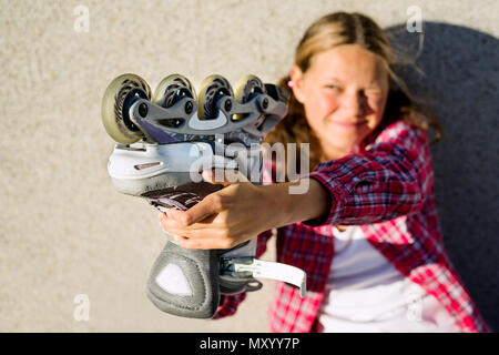 Smiling girl holding de patins dans la main. Banque D'Images