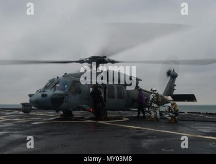 161220-N-TI017-073 OCÉAN ATLANTIQUE (déc. 20, 2016) Seaman Rudolph Coetzee ravitaille un hélicoptère Seahawk MH-60 alors que les marins s'incendie dans le poste de pilotage de la station d'amphibie Navire de débarquement USS Whidbey Island (LSD 41). L'île de Whidbey est déployée dans le cadre du Wasp du groupe amphibie, qui est de décharger le 22e MEU après un déploiement de six mois dans la flotte des États-Unis 5e et 6e secteurs d'opérations. (U.S. Photo de la marine du Maître de 2e classe Nathan R. McDonald/libéré) Banque D'Images