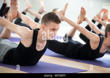 Yogi man et un groupe de jeunes sportifs pratiquant le yoga leçon, faisant poser Bow, Dhanurasana, exercice de l'exercice, piscine close up, les élèves former Banque D'Images