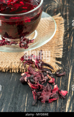 Tasse de thé hibiscus parsemé de pétales de fleurs sur fond de bois Banque D'Images