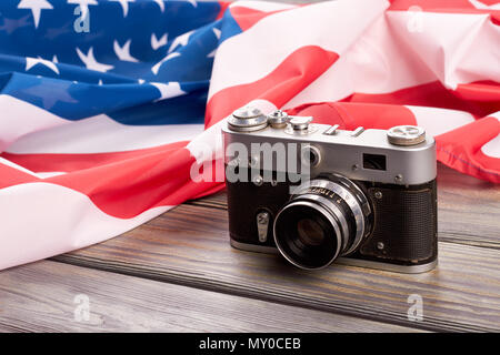 Appareil photo rétro et USA flag. Vieux film caméra et drapeau américain sur fond de bois de près. Banque D'Images