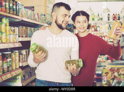 Heureux couple agréable à proximité d'étagères avec des produits en conserve par store Banque D'Images