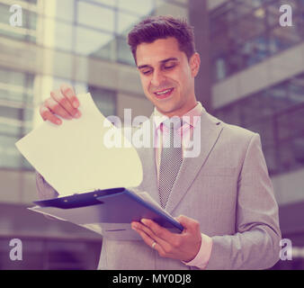 Businessman holding folder avec des documents et de contentement lecture Banque D'Images