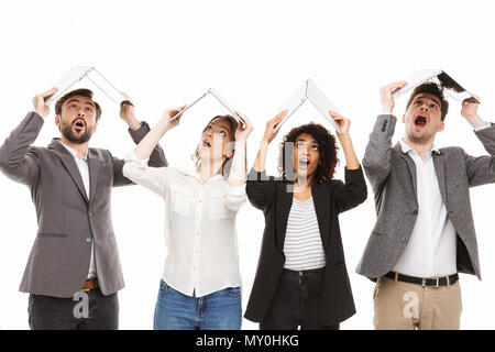 Portrait d'un groupe de gens d'affaires multiraciale choqué holding laptop ordinateurs sur leurs têtes isolées sur fond blanc Banque D'Images