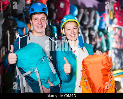 Couple de joyeux les voyageurs au magasin de sport, sacs à dos pour camping spacieux sélectionne Banque D'Images