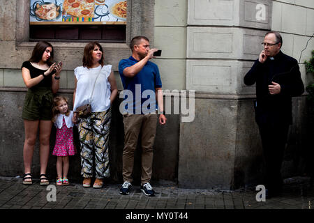 Famille de touristes regarder et enregistrer une communion à l'état humide dimanche à Barcelone, Espagne. Banque D'Images