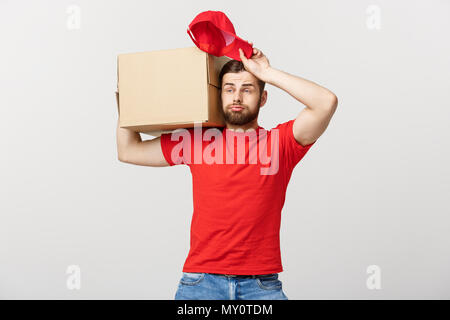 Concept de livraison : Delivery man with cases, messageries avec de l'inquiétude de l'expression du visage. Isolé sur fond gris. Banque D'Images