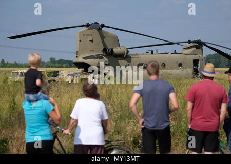 05 juin 2018, l'Allemagne, Delitzsch : spectateurs regardant le travail de chargement sur un hélicoptère des Forces armées américaines dans un champ près de la ville de Beerendorf près de Delitzsch. L'appareil avait des Chinook "d'exécuter un atterrissage forcé sur le terrain et doit faire l'objet d'une réparation sur site dans les prochains jours. La cargaison de l'hélicoptère endommagé est d'être transporté hors de la région. Photo : Sebastian Willnow/dpa-Zentralbild/dpa Banque D'Images