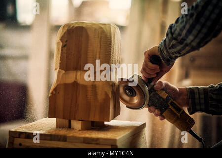 Close up d'un carpenter en vêtements de travail et de petits buiness propriétaire travaillant dans l'atelier de menuiserie, les processus d'administration avec une meuleuse d'angle , sur la tabl Banque D'Images