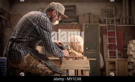 Сarpenter,petites buiness propriétaire dans les vêtements de travail bp sur la tête d'un homme avec un arbre , à l'aide d'une meuleuse d'angle à l'atelier, autour d'un lot d'outils,maisons,fu Banque D'Images