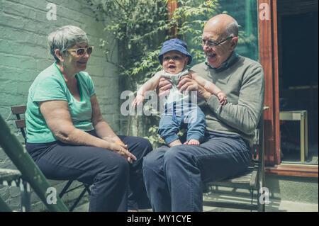 Un petit enfant qui joue avec ses grands-parents dans la cour un jour d'été Banque D'Images