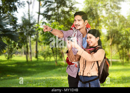 Young Asian man showing endroit agréable pour prendre des photos à sa petite amie sur le parc Banque D'Images