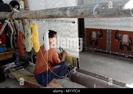 Indian homme accroupi sur le sol indien traditionnel du tissage de tapis tapis sur un métier à tisser en bois simple Rajasthan Inde Banque D'Images