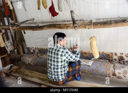 Indian homme accroupi sur le sol indien traditionnel du tissage de tapis tapis sur un métier à tisser en bois simple Rajasthan Inde Banque D'Images