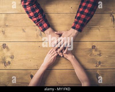 Passage tiré d'un jeune homme et femme tenant les mains sur une table en bois Banque D'Images