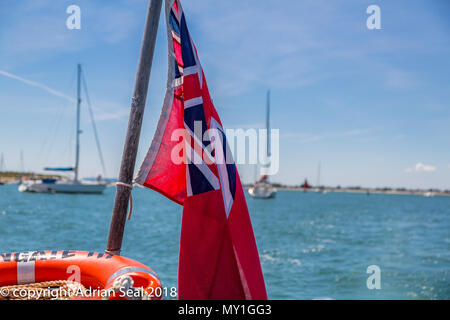 Le red ensign comme utilisé en droit maritime britannique désigne un navire civil, ici, les croisières au large de la plage de West Wittering, Sussex, England, UK Banque D'Images