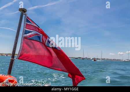 Le red ensign comme utilisé en droit maritime britannique désigne un navire civil, ici, les croisières au large de la plage de West Wittering, Sussex, England, UK Banque D'Images