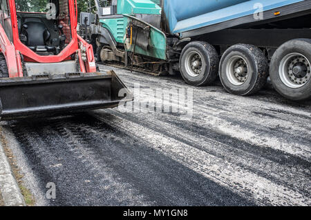 Les travaux sur la pose de l'asphalte dans la ville. Crochet de levage de la benne, camion à benne et paver machine au travail Banque D'Images