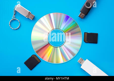 DVD avec des couleurs arc-en-ciel rougeoyant sur un panneau bleu avec les lecteurs flash USB et cartes - flatlay photography Banque D'Images