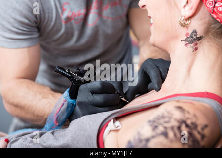 Artiste talentueux faisant le contour d'un nouveau tatouage sur la peau d'un client Banque D'Images