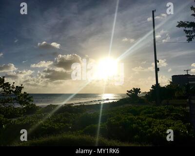 Coucher de soleil dans une rue côtière à Oistins, Barbade (île des Caraïbes) avec palmiers, plage et beau océan turquoise en arrière-plan Banque D'Images