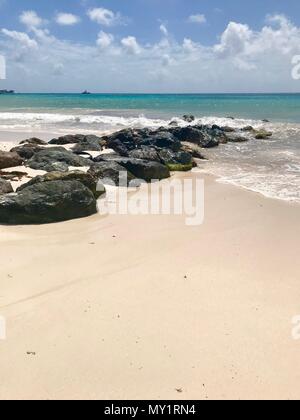 Panorama pittoresque de l'idyllique plage de Welches, Oistins La Barbade (Caraïbes) avec de grandes pierres noires / les roches, le sable blanc et une mer turquoise Banque D'Images