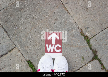 Des selfies Chaussures pieds debout sur le plancher avec isolation wc toilettes symbole sur rue . Espace libre pour le texte. Concept : la prise de décisions. Banque D'Images