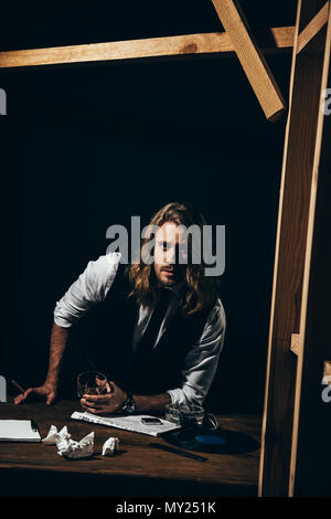 Beau barbu homme aux cheveux longs en tenue de cérémonie de fumer un cigare tout en maintenant le verre de whisky et looking at camera Banque D'Images