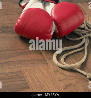 Gants de boxe rouge et la corde à sauter sur un plancher en bois rustique dans une salle de sport, de sport ou de l'affirmation de concept Banque D'Images