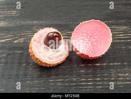 Chinese lychee fruit divisé en deux moitiés sur la table sombre Banque D'Images