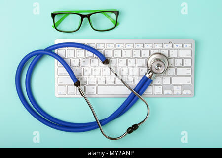 Libre de blue stethoscope couché sur le clavier de l'ordinateur portable vert et lunettes. focus sélectif. Banque D'Images