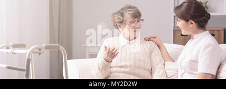 Panorama d'un senior woman parlant à un jeune, femme soignant dans un centre de réadaptation privé Banque D'Images