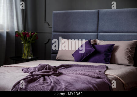 Close-up de violet couverture sur lit dans chambre féminin intérieur avec des fleurs Banque D'Images