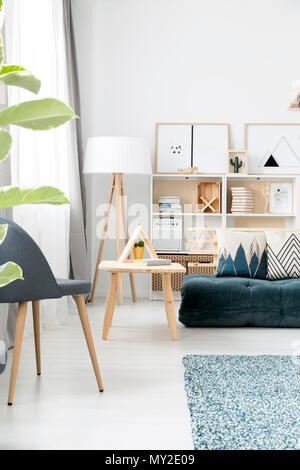 Triangle sur table en bois dans le salon intérieur avec chaise et futon vert avec des oreillers Banque D'Images