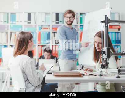 Réunion des étudiants en génie et discuter des idées dans le laboratoire, un étudiant est écrit sur un tableau. Banque D'Images