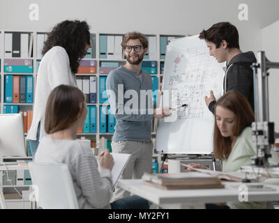 Réunion des étudiants en génie et discuter des idées dans le laboratoire, un étudiant est écrit sur un tableau. Banque D'Images