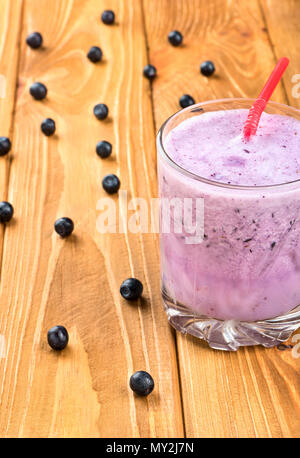 Verre de smoothie aux bleuets frais aux fruits rouges éparpillées sur la table Banque D'Images